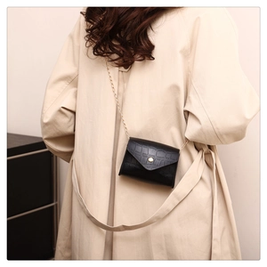 Detail of crossbody small square bag with crocodile pattern and gold chain strap on model