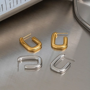 Minimalist U-shaped geometric earrings in gold and silver finish on metallic background
