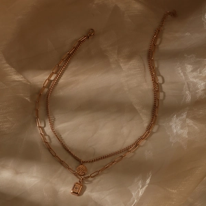 Close-up of double layer gold necklaces with round and square starburst pendants on silk