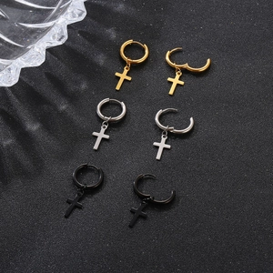 Close-up of titanium steel cross hoop earrings in gold, silver, and black on dark surface