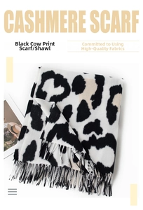 Close-up of soft black and white cow print scarf fabric with elegant tassel fringe detail