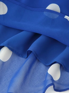 Détail du tissu en mousseline bleue à pois avec plis élégants et finitions cousues