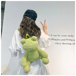 Green plush frog backpack shown on model featuring cute cartoon eyes and soft texture