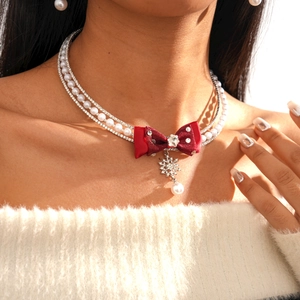 Detail of a layered necklace with red velvet bow, rhinestone snowflake and pearls
