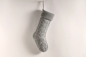 Close-up of grey cable-knit Christmas stocking with textured weave and hanging loop