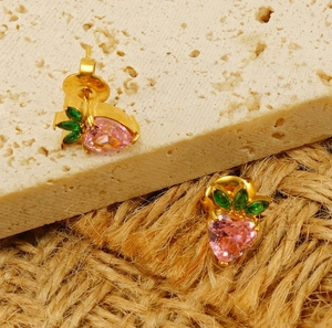 Macro view of strawberry stud earring with pink heart crystal and green leaves detail