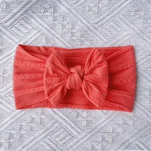 Detailed texture of coral pink cable knit nylon headband with large bow for babies