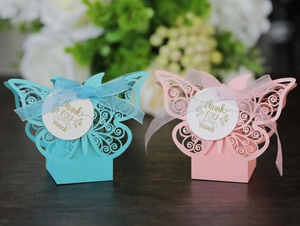 Close-up of laser-cut butterfly gift boxes with ribbons in pink and blue colors
