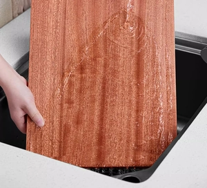 Close-up of washing a rectangular ebony wood cutting board under flowing water