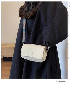 White lychee leather shoulder bag with colorful woven strap and gold metal hooks