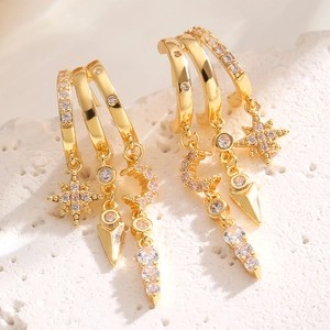 Macro detail of gold layered star and moon earrings with cubic zirconia charms