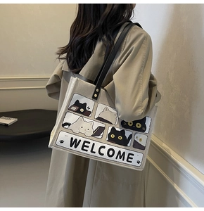 Detail of beige canvas tote with cat illustrations and black PU leather shoulder straps