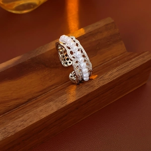Macro detail of silver-finish ring with multiple pearls and openwork metal hollow pattern