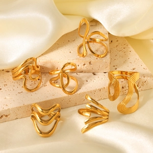 Exaggerated 18K gold plated stainless steel rings displayed on travertine and silk fabric