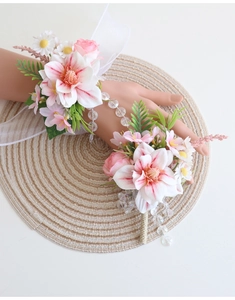 Détail d'un bracelet de fleurs artificielles roses et blanches avec perles et ruban de soie