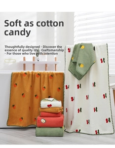 Close-up of soft coral fleece towels with cute fruit embroidery including strawberry and cherry