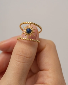 Detailed macro view of gold beaded double-ring with sunburst star and blue stone