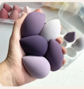 Close-up of hand holding a purple teardrop makeup sponge made of hydrophilic polyurethane