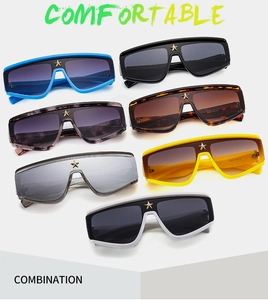 Detail shot of oversized shield sunglasses featuring a metallic star on the frame nose bridge