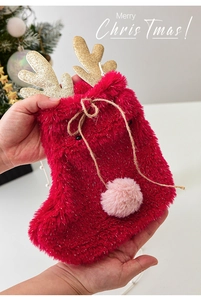 Close-up of plush red reindeer Christmas gift bag with gold glitter antlers and drawstring