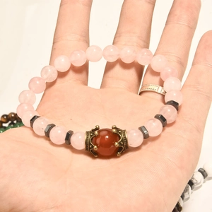 Primo piano di perle in quarzo rosa e pietra rossa su un bracciale bohémien
