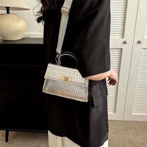 Silver crocodile pattern handbag with gold twist lock and grey strap worn by model