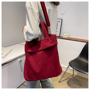 Detail of a dark red nylon canvas tote bag worn by a model in a modern home setting