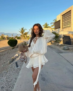 Outdoor shot of a cream satin ruffled dress with long sleeves and layered hemline