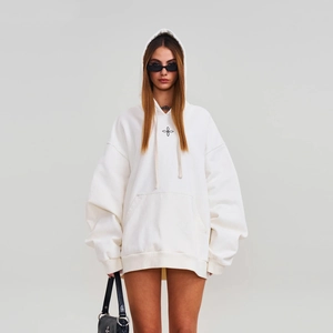 Vue détaillée du sweat à capuche oversize crème avec un logo floral noir minimaliste