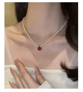 Détail d'un collier de perles vintage avec pendentif en agate rouge sur mannequin
