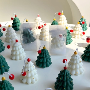 Mini Christmas tree candles in green and white with festive ornaments in gift boxes