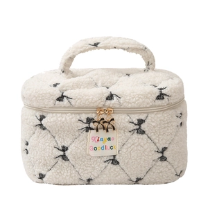 White faux shearling makeup bag with black bow pattern and golden zip detail