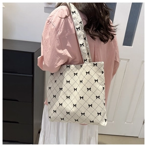 Dettaglio della borsa tote in velluto beige con fiocchi neri e cuciture trapuntate