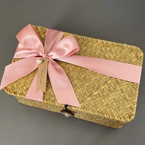 Detailed texture of rectangular woven seagrass gift box with pink bow and tag