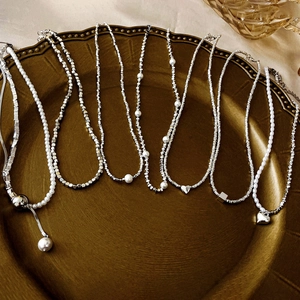 Detail showing assorted silver-tone heart and pearl fringe necklaces on a vintage tray