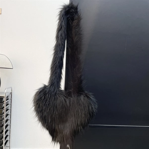 Macro shot of fluffy black heart-shaped faux fur bag texture and long plush shoulder strap