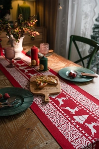 Detailed texture of red Christmas table runner with white reindeer and snowflake motifs