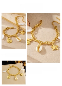 Close-up of gold chain bracelet with starfish, conch, seashell and pearl charms