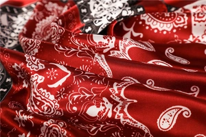 Close-up of paisley pattern silk scarf texture with glossy red and black fold details