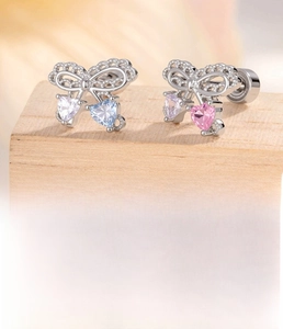 Detail of silver bow earrings featuring pink and blue heart-shaped cubic zirconia stones