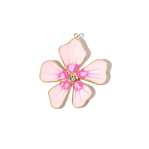 Detail of pink enamel flower pendant with golden frame and sparkling center rhinestone