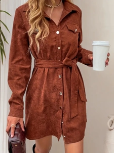 Detail of reddish brown corduroy shirt dress featuring waist belt and front button pocket
