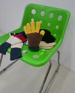 Surtido de guantes de lana de colores lisos en una silla verde de estilo minimalista