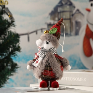 Dettaglio dell'orso natalizio in peluche con campanello dorato e decorazioni in tessuto