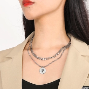Detail of silver double-layered necklace with cuban chain and retro queen coin pendant