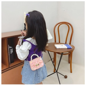 Pink girl's crossbody bag with pearl handle and rabbit decor shown in a cozy home setting