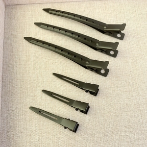 Set of 6 black metal hair clips in large and small sizes for styling on beige background