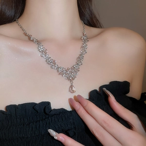 Close-up of elegant silver floral necklace with pink teardrop crystal on model neck