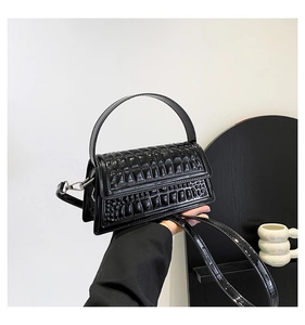 Close-up of black crocodile pattern handbag with glossy finish and silver hardware
