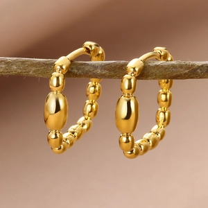 Macro shot of 18k gold plated beaded hoop earrings hanging on a rustic tree branch